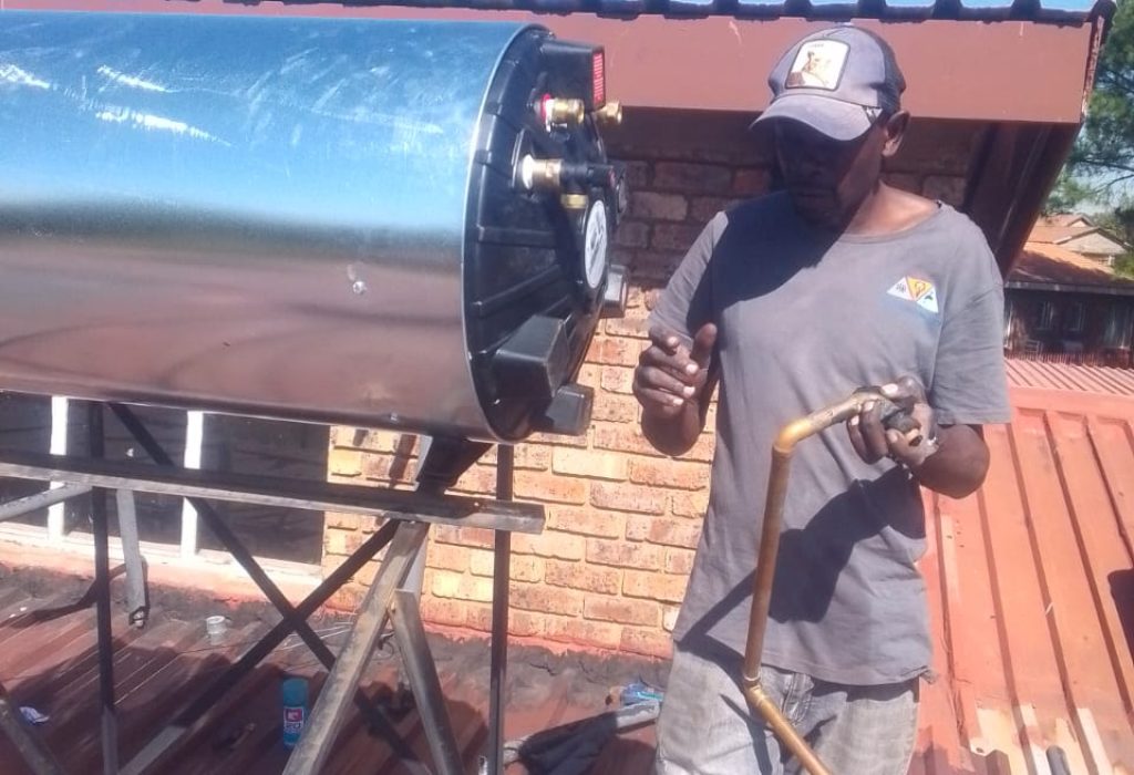 Plumber installing a solar geyser on a roof