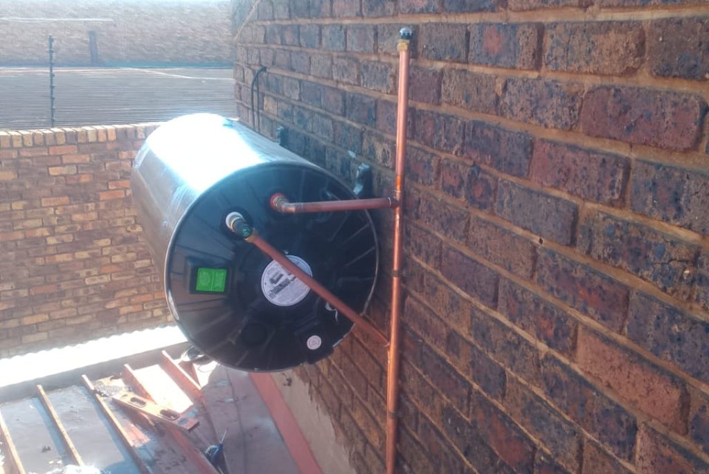 Technician installing a solar water heater on a rooftop in Pretoria