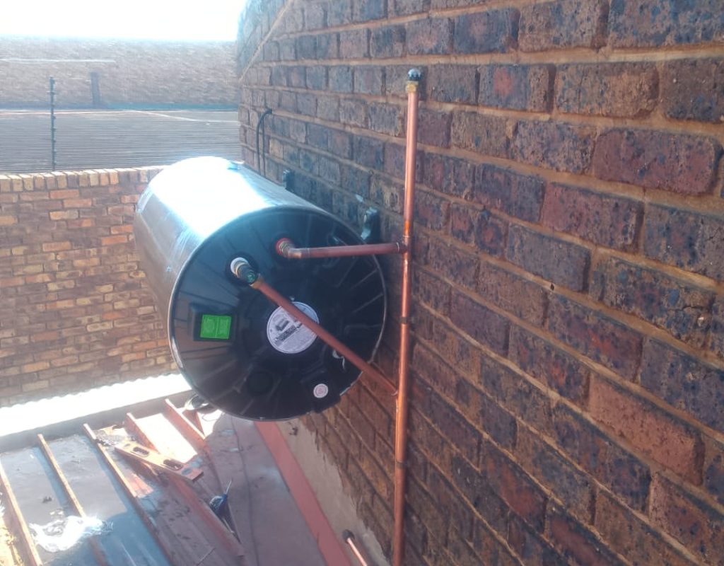 Technician installing a solar water heater on a rooftop in Pretoria